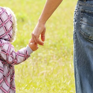 Child walking while holding the hand of his father - Vacanti Shattuck Finocchiaro Attorneys.